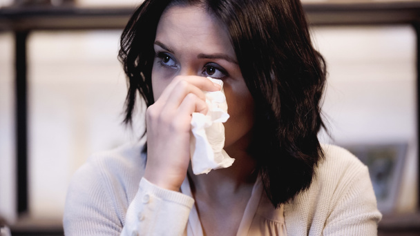 crying brunette woman wiping tears with paper napkin at home - Photo, Image