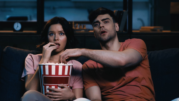 uomo raggiungendo popcorn in secchio e guardando film con la ragazza  - Foto, immagini