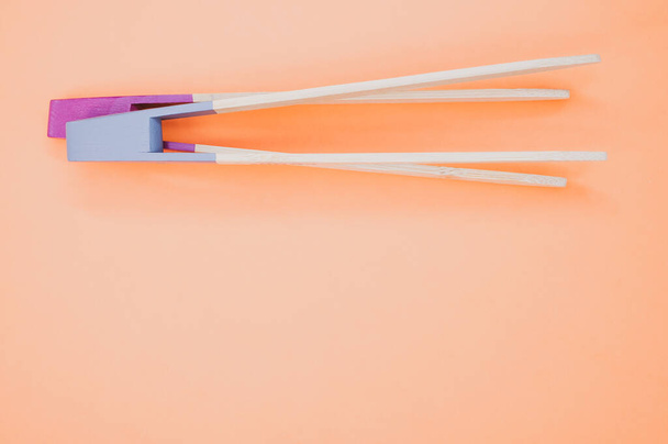 A closeup of two wooden coo chopsticks on an orange surface - Fotografie, Obrázek