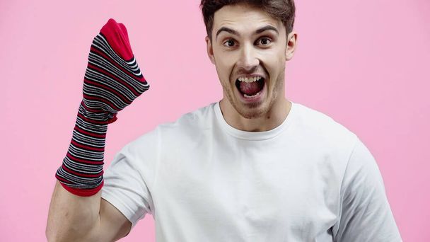 Amazed man with sock on hand looking at camera isolated on pink  - Photo, Image