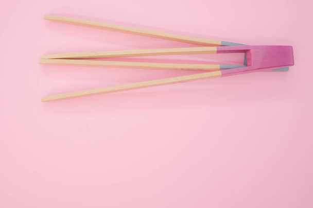 A closeup of two wooden cooking chopsticks on a pink surface - Foto, afbeelding