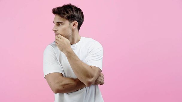 Brunette man in wit t-shirt kijken weg geïsoleerd op roze - Foto, afbeelding