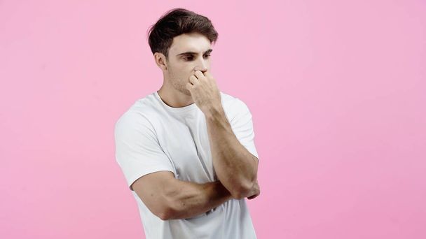 Pensive and worried man with hand near mouth looking away isolated on pink - Photo, Image