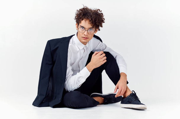 a guy in a classic suit and glasses sits on the floor In a bright room. High quality photo - Photo, Image