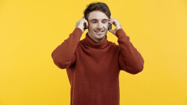 Homem feliz ouvindo música em fones de ouvido isolados no amarelo  - Foto, Imagem