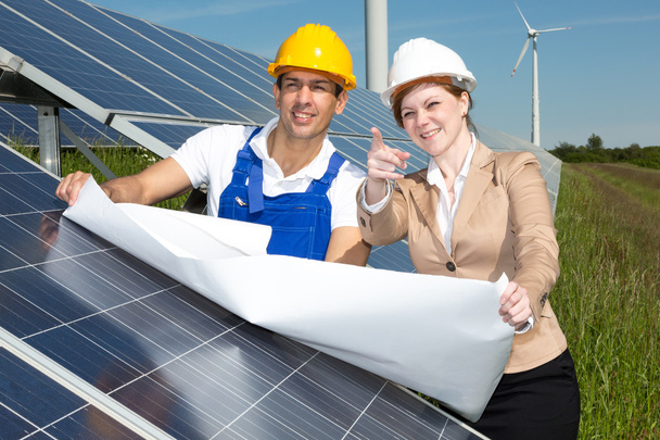 Ingénieurs photovoltaïques avec plan de construction aux panneaux solaires
 - Photo, image