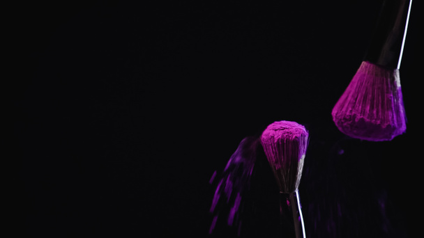 cosmetic brushes with deep purple powder on black background - Fotó, kép