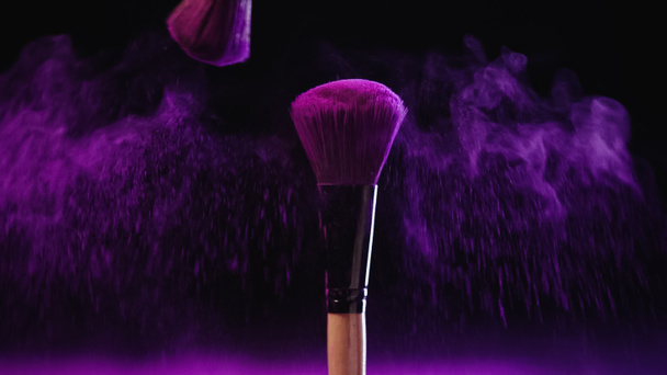 soft cosmetic brushes with holi paint near pink splash of dust on black background - Foto, Imagem