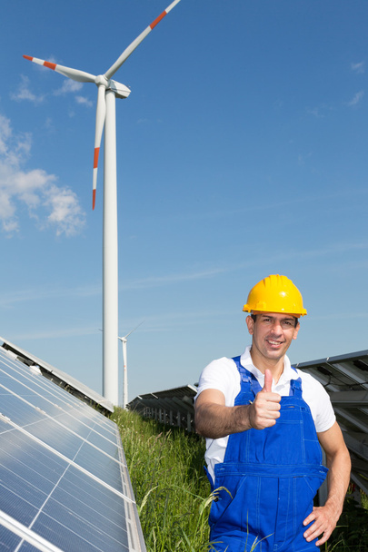 Engineer at energy park with solar panels and wind turbine - Photo, image