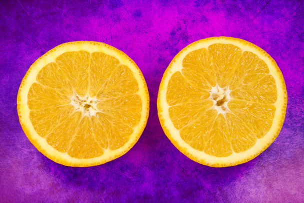 Two halves of fresh orange fruit on grunge purple background - Fotoğraf, Görsel