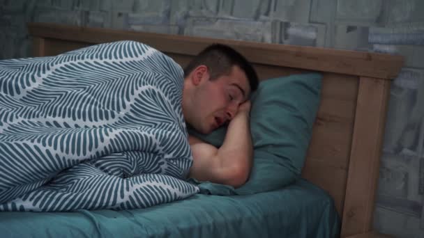 Ein Mann wacht morgens im Bett auf und gähnt - Filmmaterial, Video