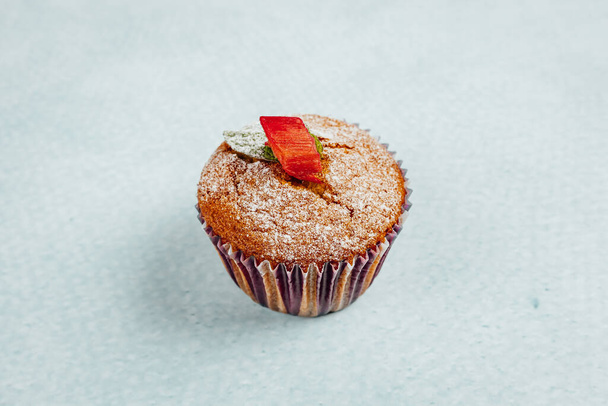 A closeup shot of a delicious muffin with sugar powder on a turquoise surface - Foto, immagini