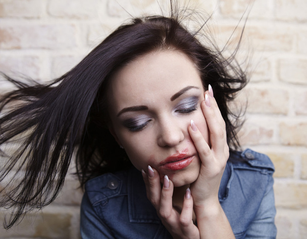 Depressed young brunette with smeared lipstick on her face. - Foto, Bild