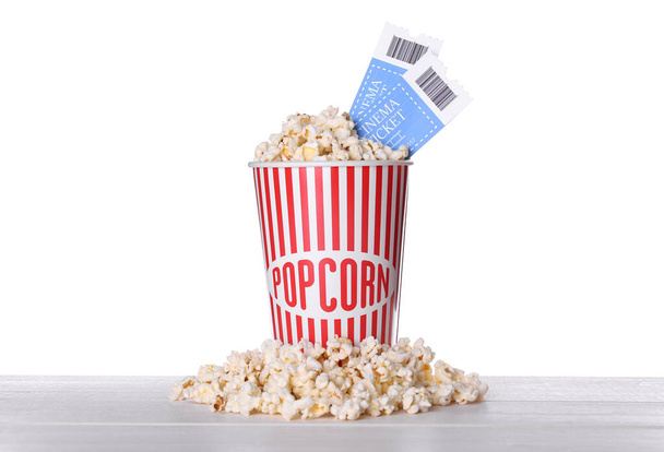 Delicious popcorn with tickets on wooden table against white background - 写真・画像