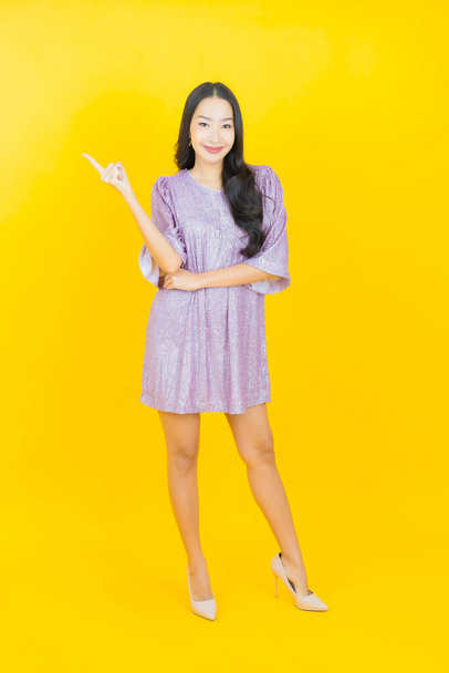 Porträt schöne junge asiatische Frau lächeln mit Aktion auf farbigem Hintergrund - Foto, Bild