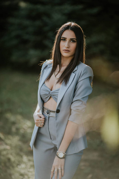 A pretty Caucasian lady wearing a gray crop top and blazer and posing in the park - Фото, зображення