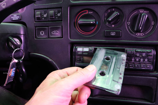 Водій вставляє касету в магнітофон у старій машині
. - Фото, зображення
