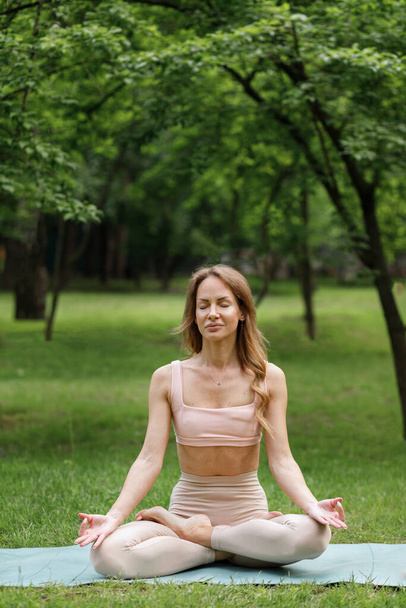 Young woman in the park in the summer engaged in yoga and meditating - Fotografie, Obrázek