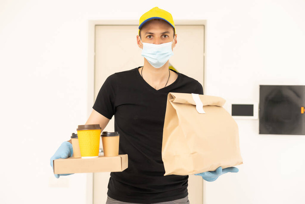 delivery man holding package to deliver. Courier hand holding brown box isolated on grey background. Detail of delivery man carrying cardboard parcel with label with copy space. - Foto, Bild