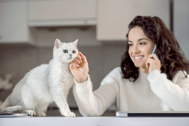 Cute woman talking on the phone and stroking her cat - Photo, Image