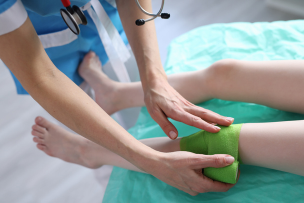 Traumatólogo aplica vendaje a niño lesionado pierna - Foto, imagen