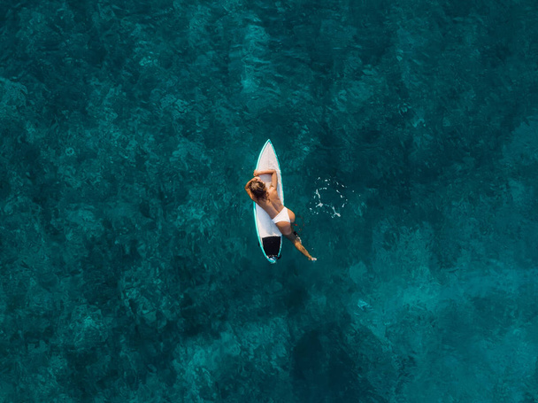 Sexy surfer woman relaxing with surfboard in tropical ocean. Aerial view with surf girl - Photo, Image