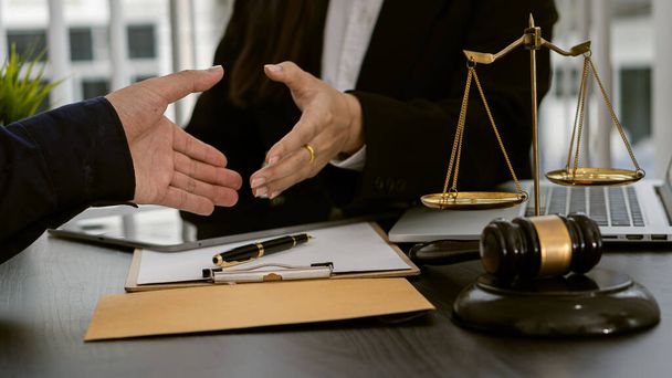 Консультант-юрист пожимает руку бизнесмену в офисе с судьей молотком и шкалой судьи с концепцией юриста-ноутбука и юридическим консультантом - Фото, изображение