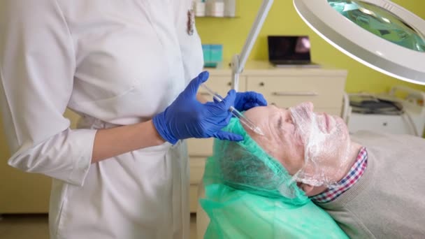 Hombre de mediana edad obteniendo procedimiento de biorevitalización en clínica de belleza - Imágenes, Vídeo