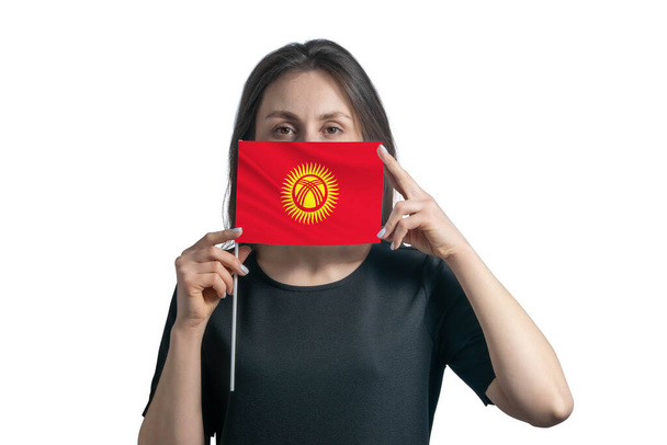 Happy young white woman holding flag Kyrgyzstan flag and covers her face with it isolated on a white background. - Photo, Image
