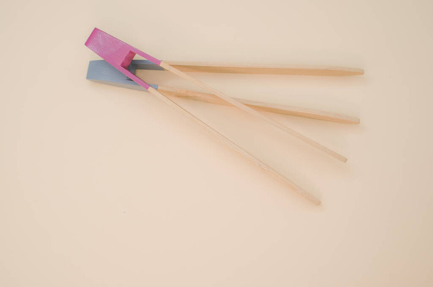 A closeup of two wooden cooking chopsticks on a cream surface - Foto, Bild