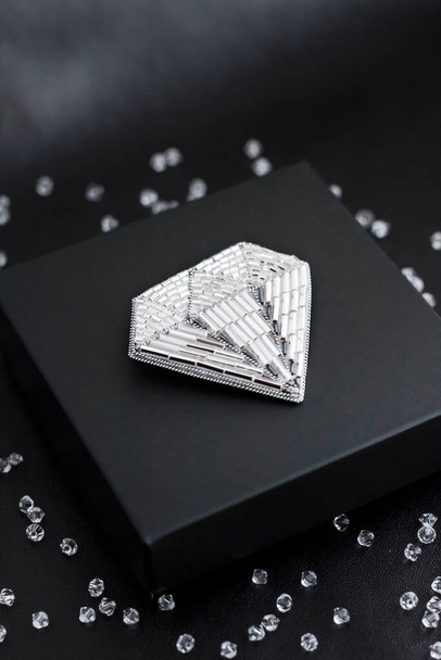 Broche brodée de perles de graines en forme de diamant sur fond noir - Photo, image