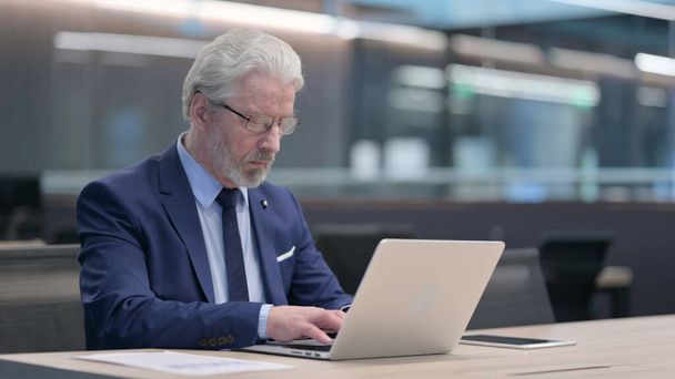 Ancien homme d'affaires travaillant sur ordinateur portable dans le bureau - Photo, image