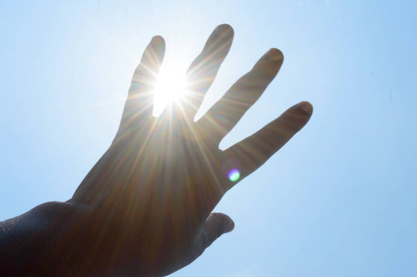 Gorące letnie promienie słoneczne zalewają ludzką dłoń. Ręczne przykrycie temperatury światła słonecznego. Ochrona przed światłem ultrafioletowym i oparzeniami słonecznymi. Udar słoneczny, udar cieplny, efekt cieplarniany. - Zdjęcie, obraz