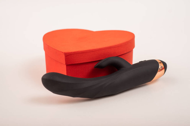 Black dildo and heart-shaped box on a white background - Foto, afbeelding