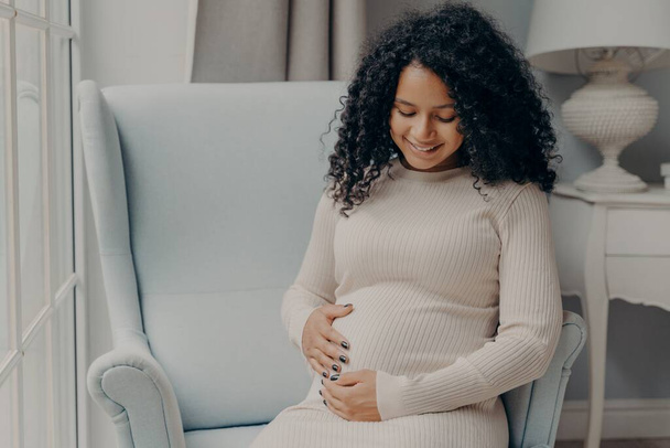 Jolie femme afro-américaine tenant son ventre en prévision du futur bébé - Photo, image