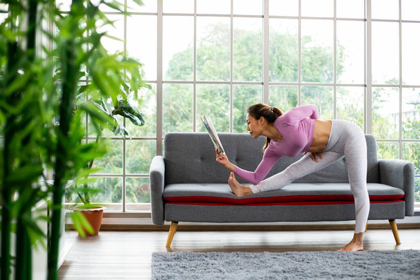 Aziatische vrouw post yoga een voor het beoefenen en lezen van tijdschrift in de huiskamer.Thaise oefening thuis. - Foto, afbeelding