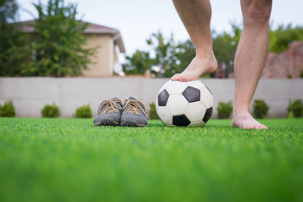人工芝に対する認識できない裸足のサッカー選手の足。サッカーボールストリートサッカーシューズ。スペースのコピー. - 写真・画像