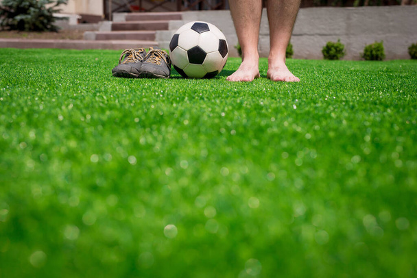 Ноги неузнаваемого босоногого футболиста против искусственной травы. Футбольный мяч, обувь для уличного футбола. Копирование пространства. - Фото, изображение