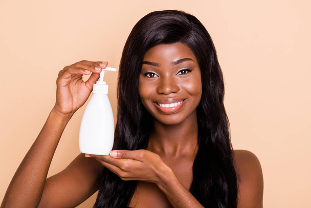 Photo of charming sensual lady hold shampoo soap bottle look camera shiny white smile isolated beige background - Foto, afbeelding
