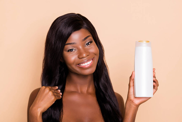 Portrait of attractive healthy shine cheerful long-haired girl holding shampoo smoothing effect isolated over beige pastel color background - Fotó, kép