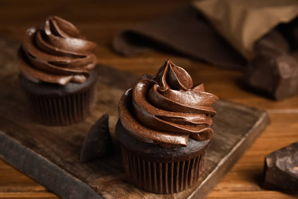 Delicious chocolate cupcakes with cream on wooden table - Fotografie, Obrázek