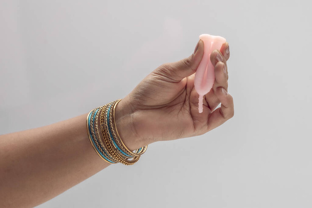 Yeniden kullanılabilir silikon adet bardağını tutan Hintli bir kadın farklı türde katlama gösteriyor.. - Fotoğraf, Görsel