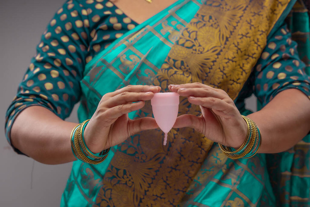 Yeniden kullanılabilir silikon regl bardağı tutan Hintli bir kadın ve farklı türde katlamalar gösteriyor.. - Fotoğraf, Görsel