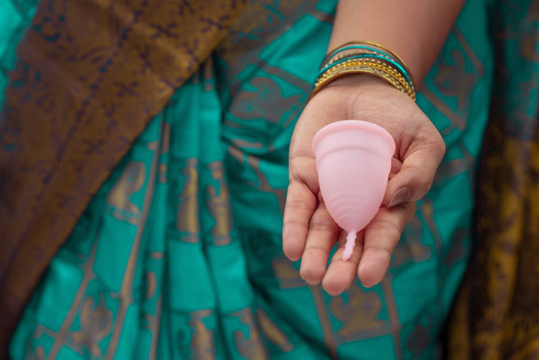 Yeniden kullanılabilir silikon regl bardağı tutan Hintli bir kadın ve farklı türde katlamalar gösteriyor.. - Fotoğraf, Görsel