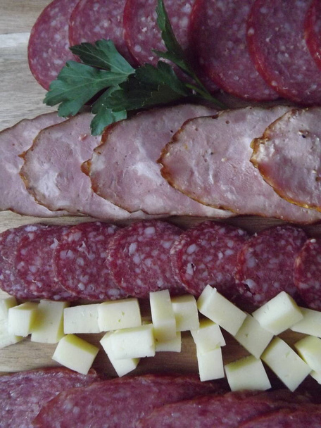 slicing smoked sausage of four varieties with cheese and red and yellow tomatoes and cherry tomatoes - Photo, Image