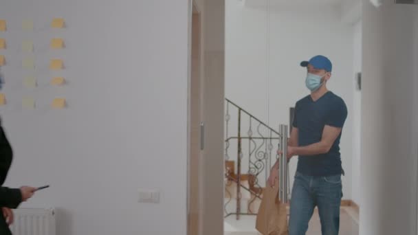 Leverancier met bescherming gezichtsmasker houden POS terminal leveren afhaalmaaltijden bestelling - Video