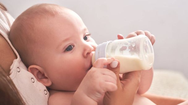 Mom feeds her happy child son baby milk powder, baby bottle - Foto, afbeelding