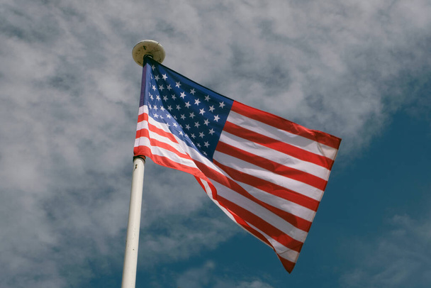Σημαία των Ηνωμένων Πολιτειών γκρο πλαν στο μπλε φόντο του ουρανού - Φωτογραφία, εικόνα