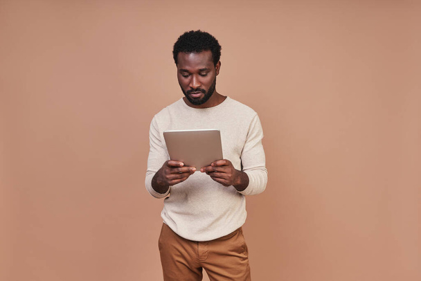 Confident young African man in casual clothing using digital tablet - Φωτογραφία, εικόνα