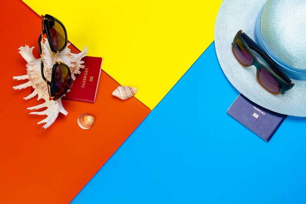 Accesorios de playa con gafas de sol, pasaportes, sombrero de paja y conchas sobre un fondo de color. Vacaciones de verano. Fondo de verano. - Foto, Imagen